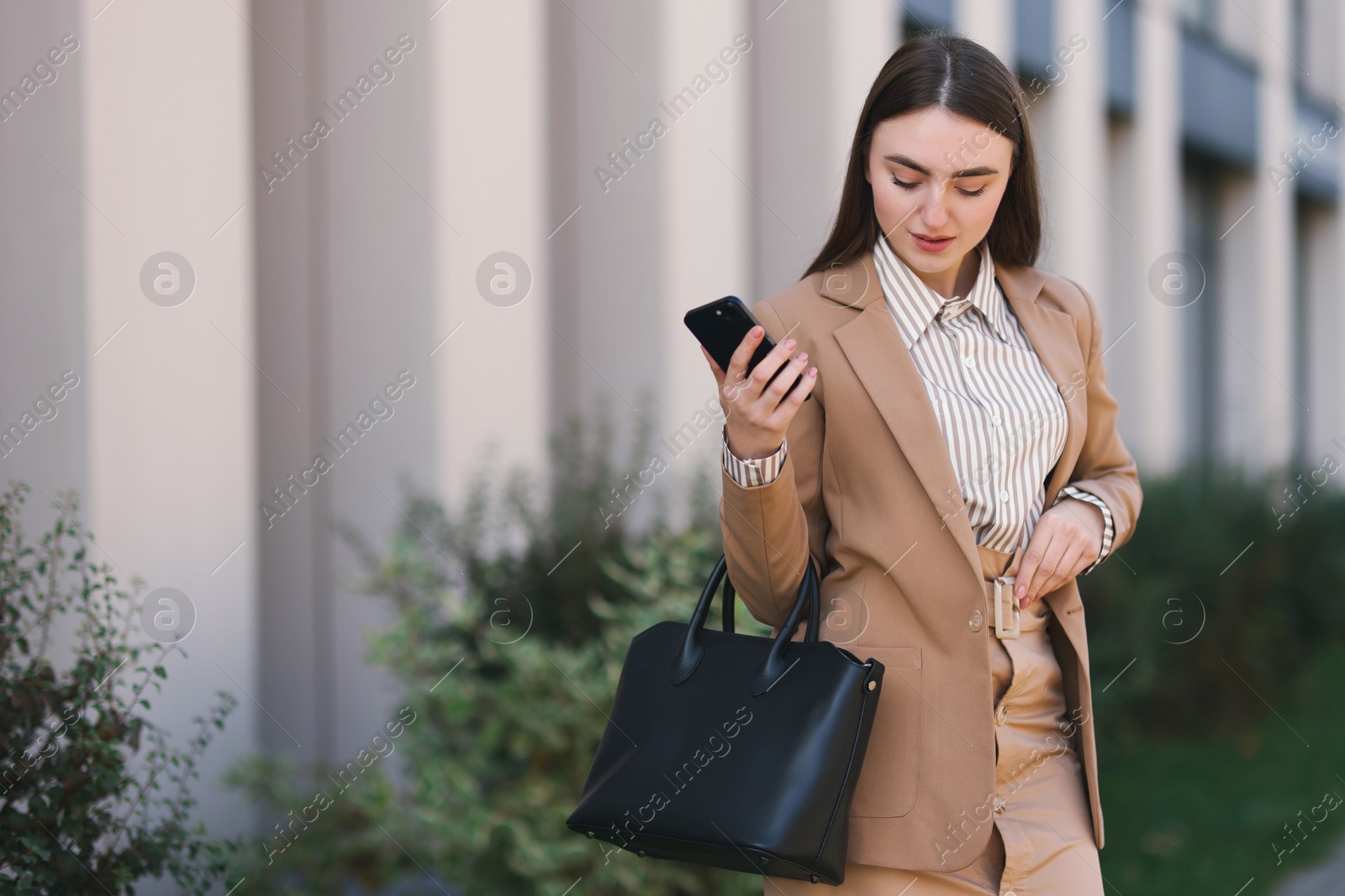 Photo of Businesswoman in stylish suit with smartphone outdoors. Space for text