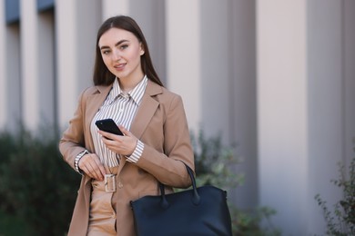 Photo of Businesswoman in stylish suit with smartphone outdoors. Space for text