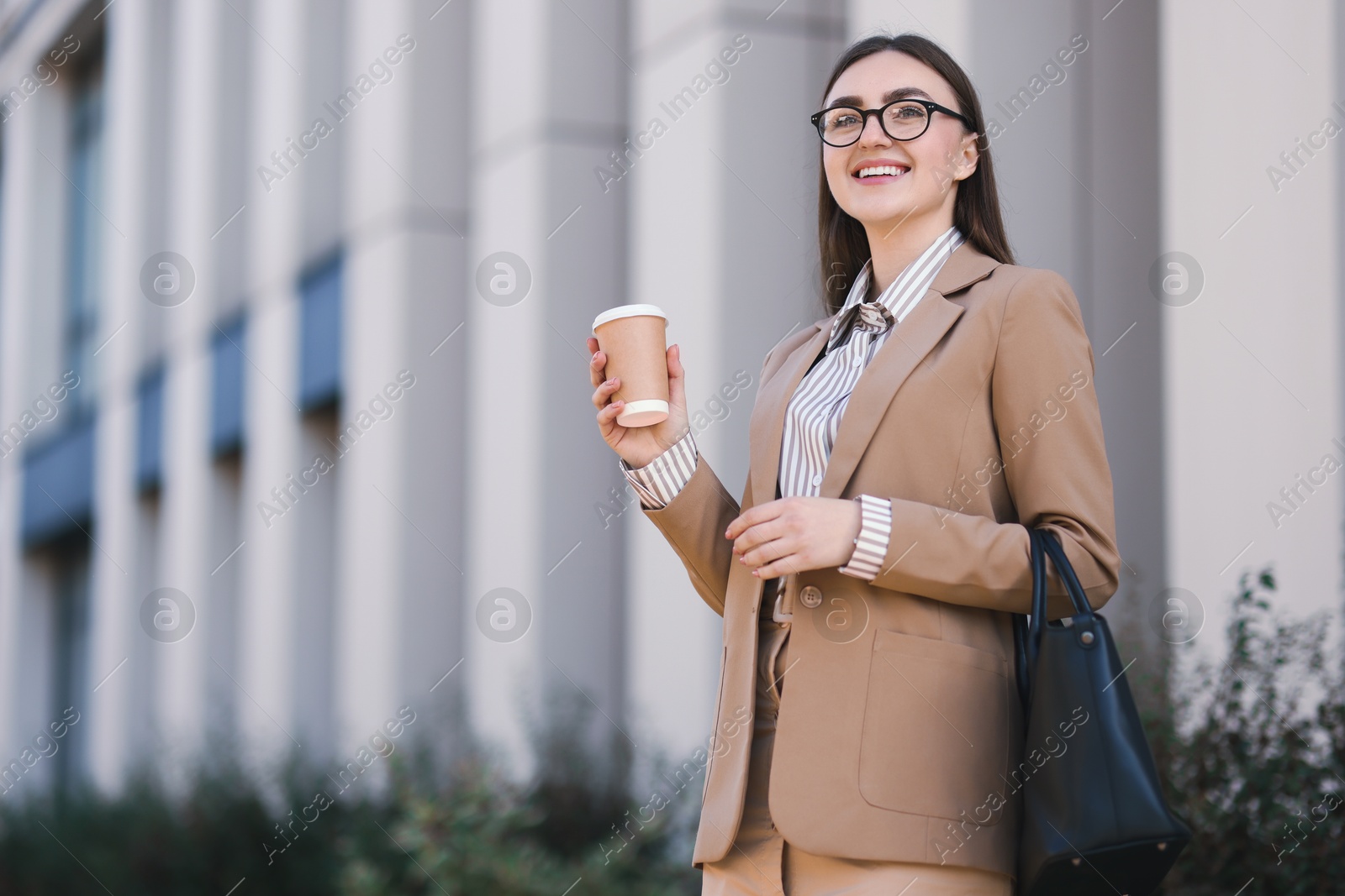 Photo of Smiling businesswoman in stylish suit with paper cup outdoors, low angle view. Space for text