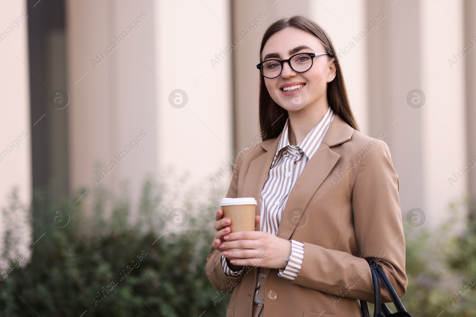 Photo of Beautiful woman in stylish suit with paper cup outdoors. Space for text