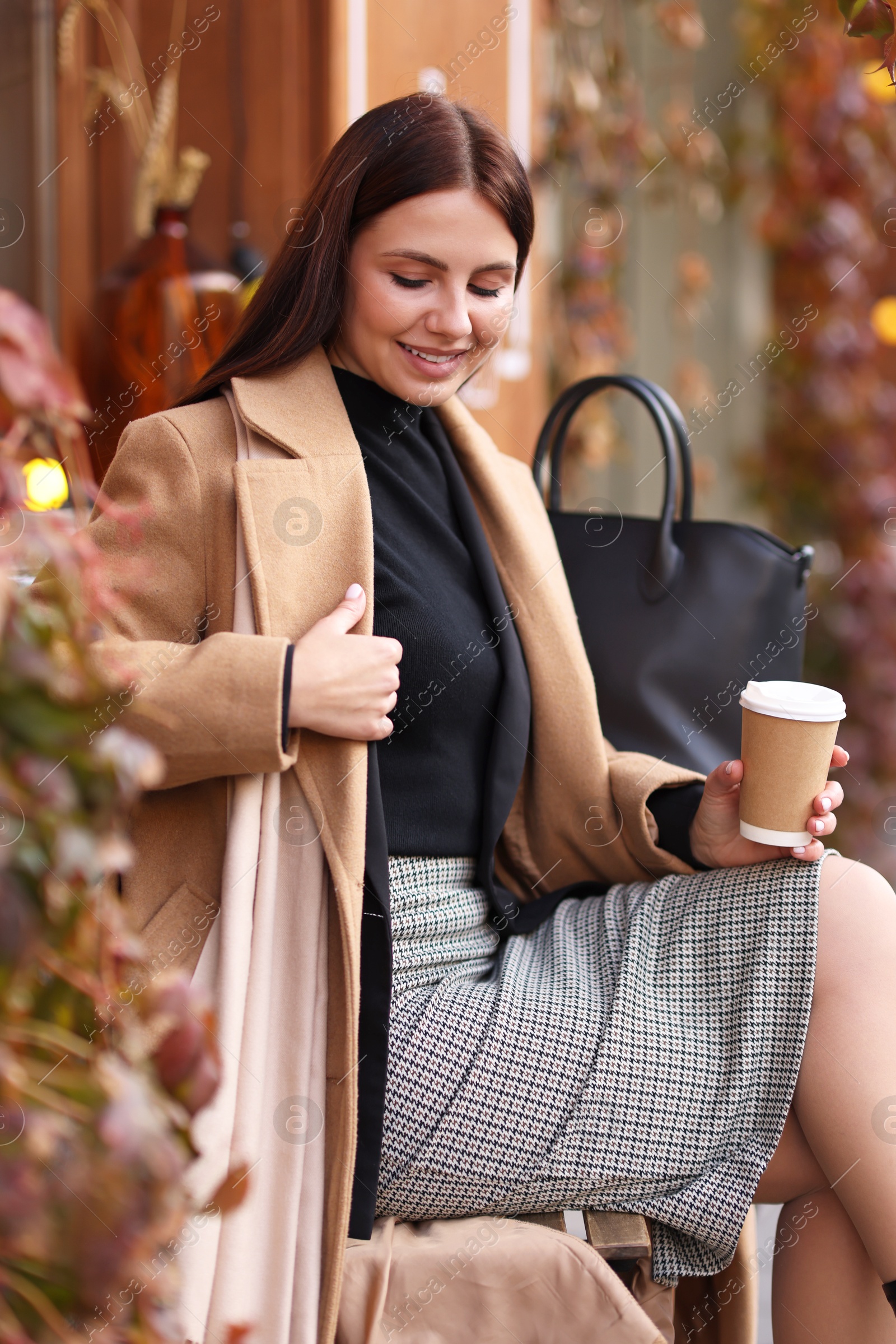 Photo of Smiling businesswoman in stylish suit with paper cup in outdoor cafe