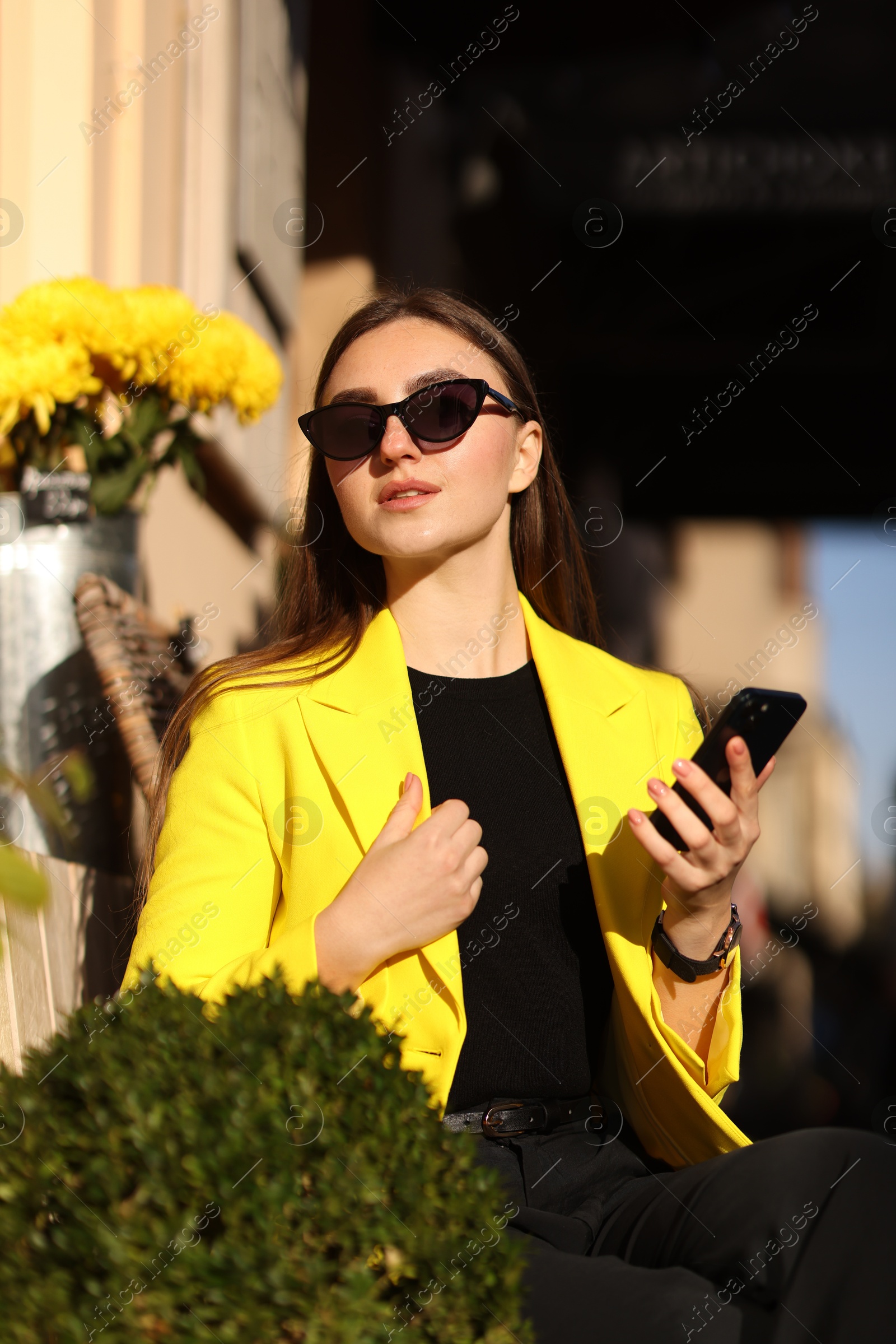 Photo of Businesswoman in stylish suit with smartphone outdoors on sunny day