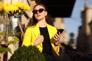 Photo of Businesswoman in stylish suit with smartphone outdoors on sunny day