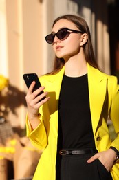 Photo of Businesswoman in stylish suit with smartphone outdoors on sunny day