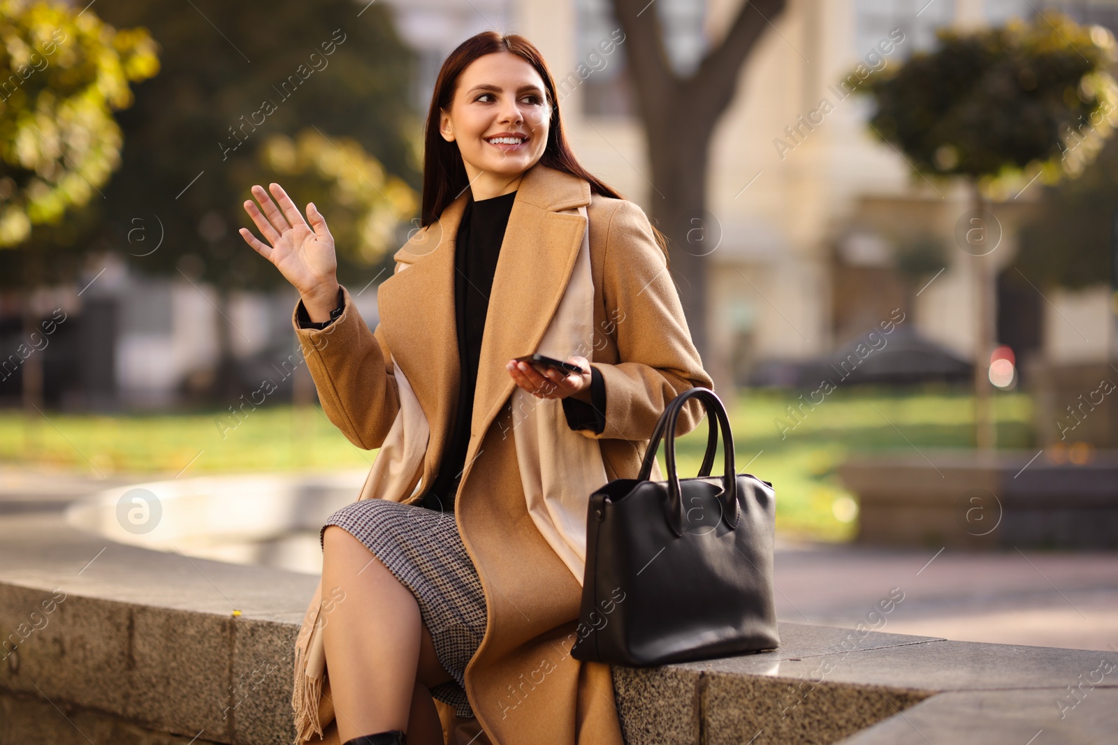 Photo of Smiling businesswoman in stylish suit waving hello outdoors