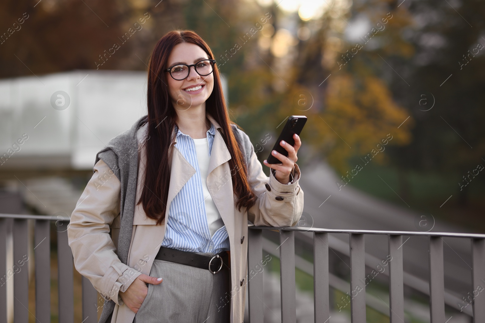 Photo of Smiling businesswoman in stylish suit with smartphone outdoors. Space for text