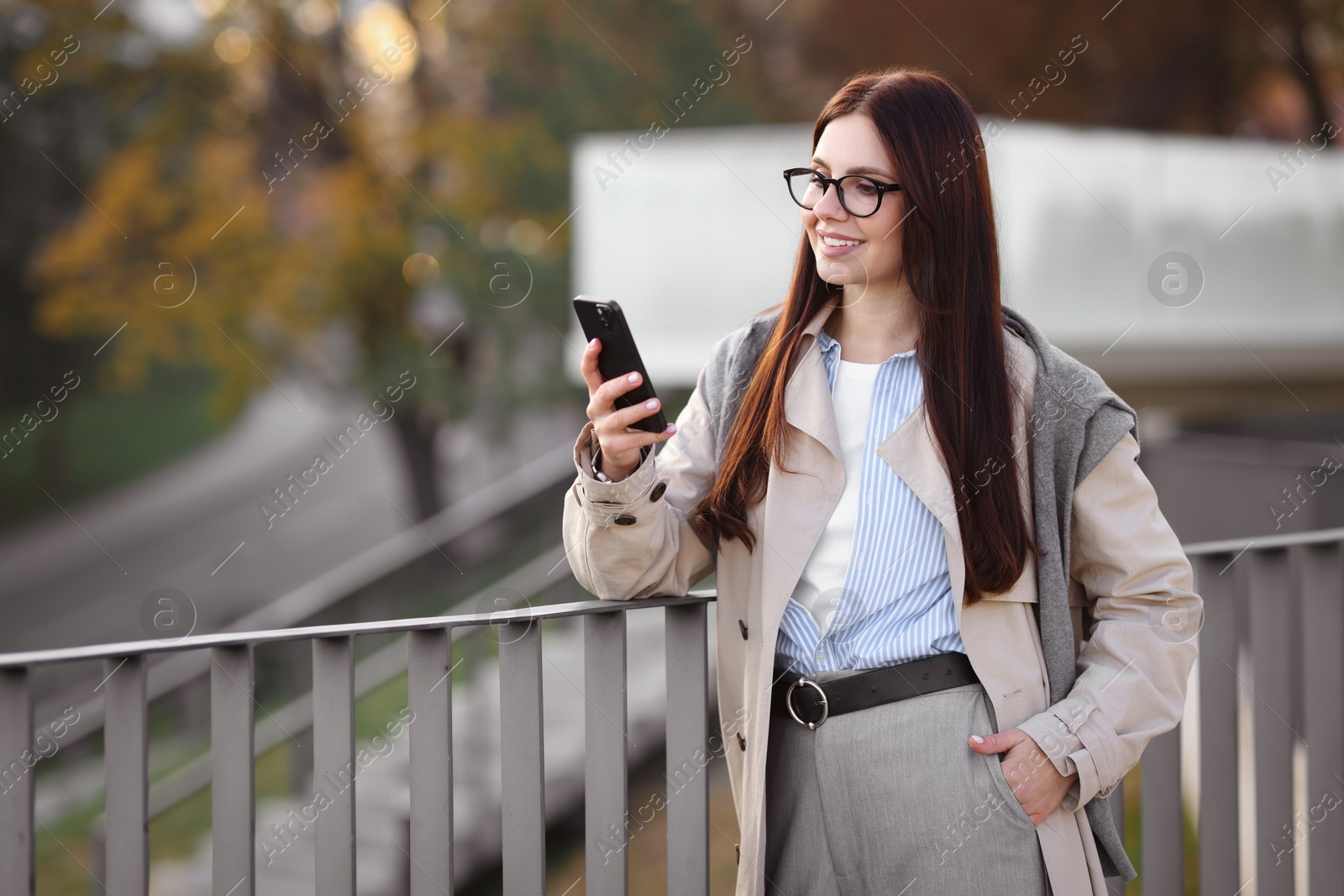 Photo of Smiling businesswoman in stylish suit with smartphone outdoors. Space for text