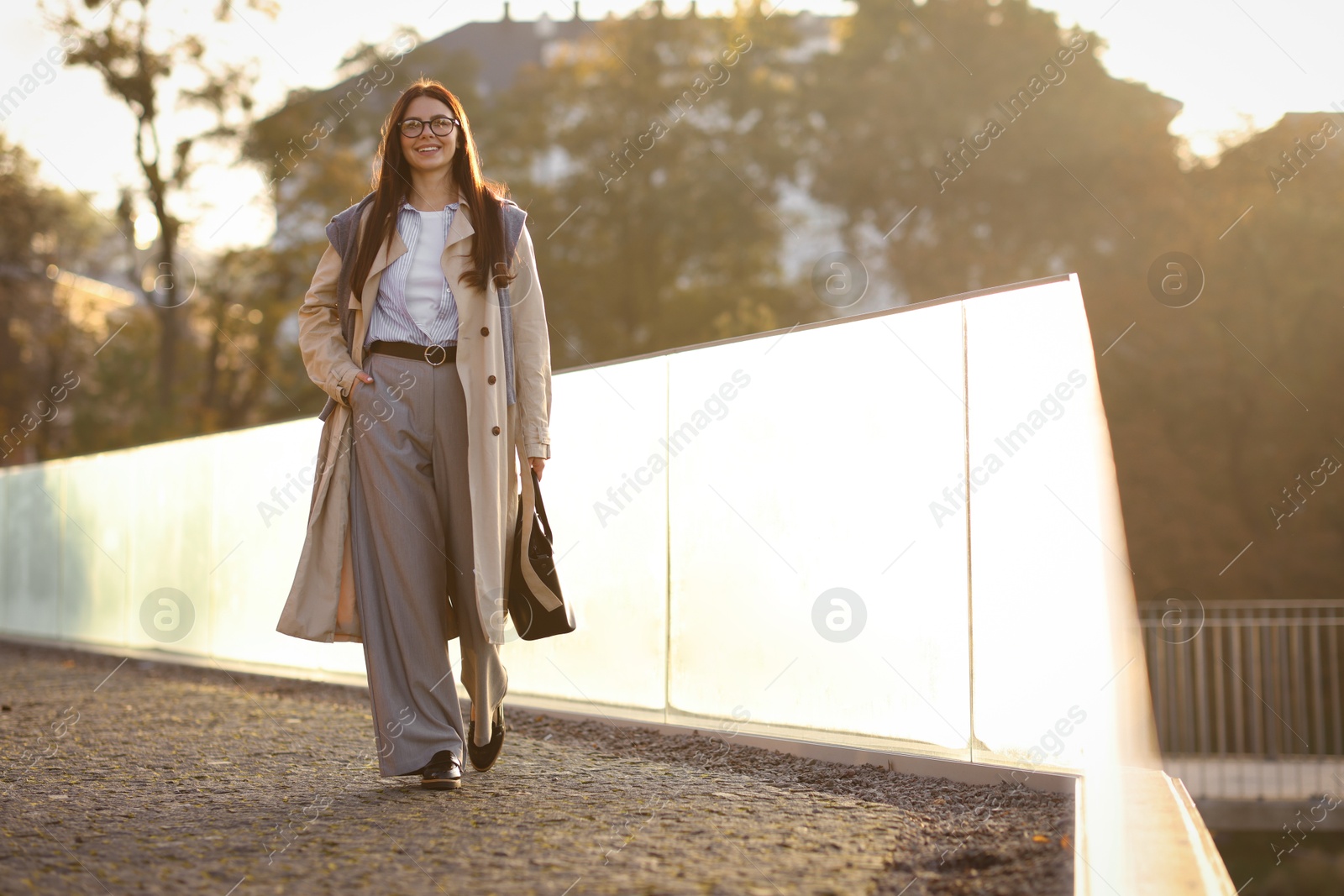 Photo of Smiling businesswoman in stylish suit walking outdoors at morning. Space for text