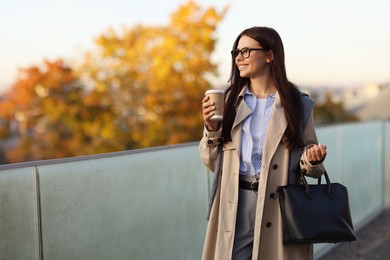 Photo of Beautiful woman in stylish suit with paper cup outdoors. Space for text