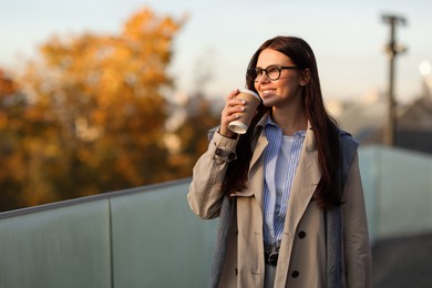 Photo of Beautiful woman in stylish suit with paper cup outdoors. Space for text