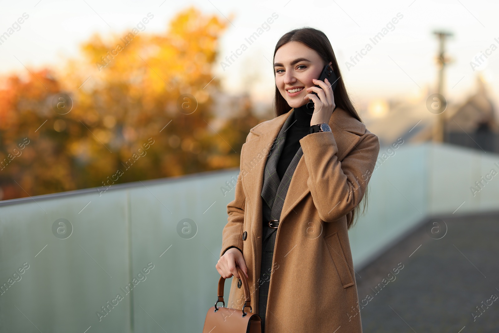 Photo of Beautiful woman in stylish suit talking on smartphone outdoors. Space for text