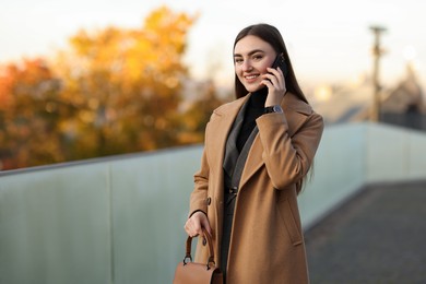 Photo of Beautiful woman in stylish suit talking on smartphone outdoors. Space for text