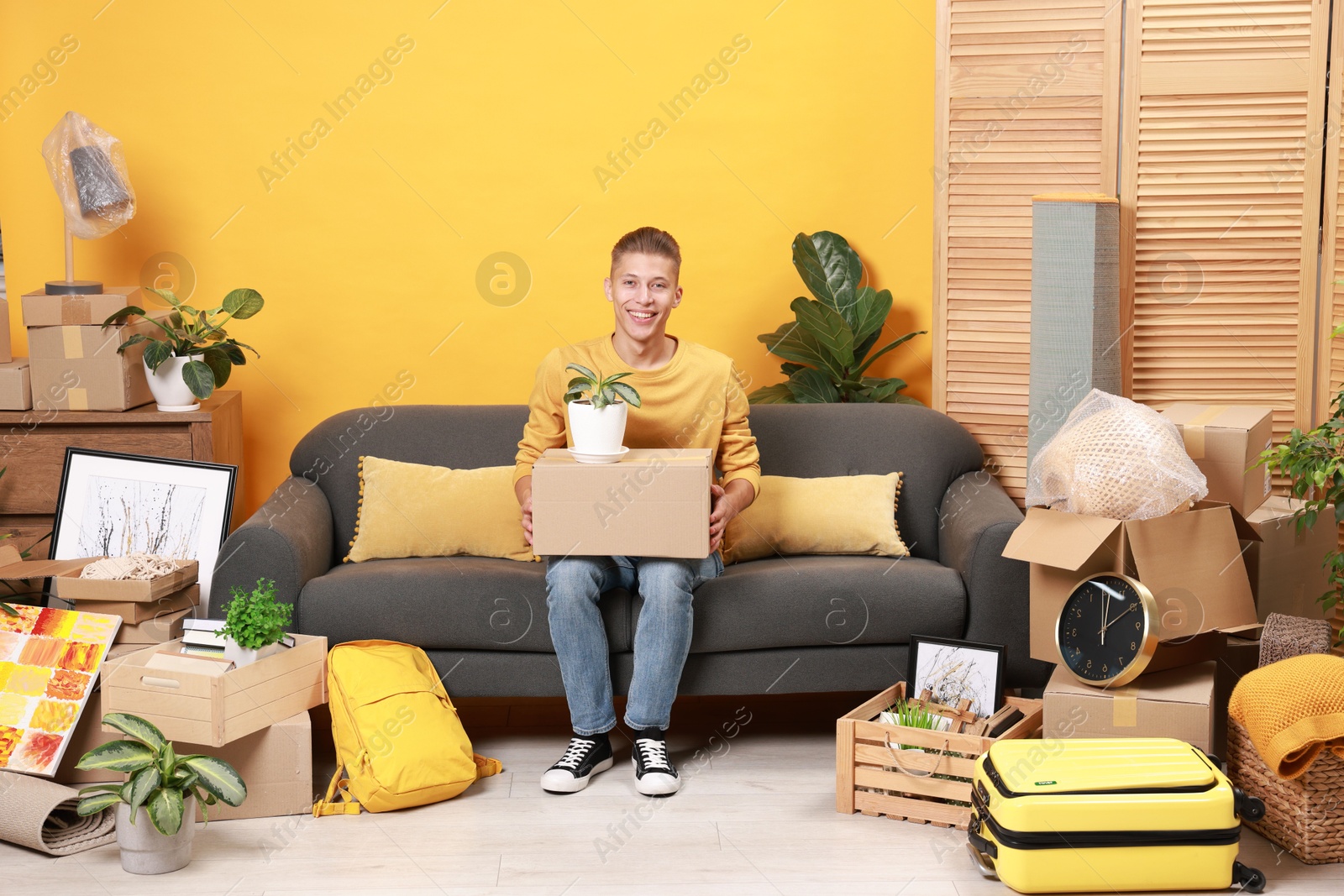 Photo of Happy man with different stuff in new apartment. Housewarming party