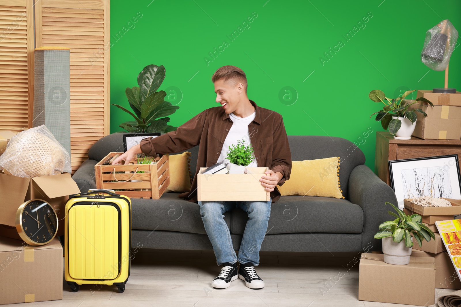 Photo of Happy man with different stuff in new apartment. Housewarming party