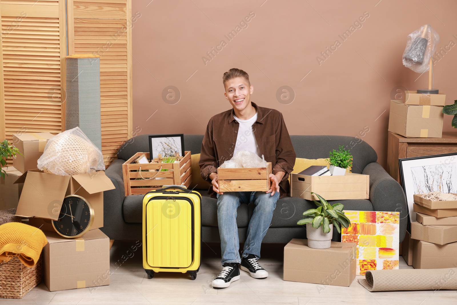 Photo of Happy man with different stuff in new apartment. Housewarming party