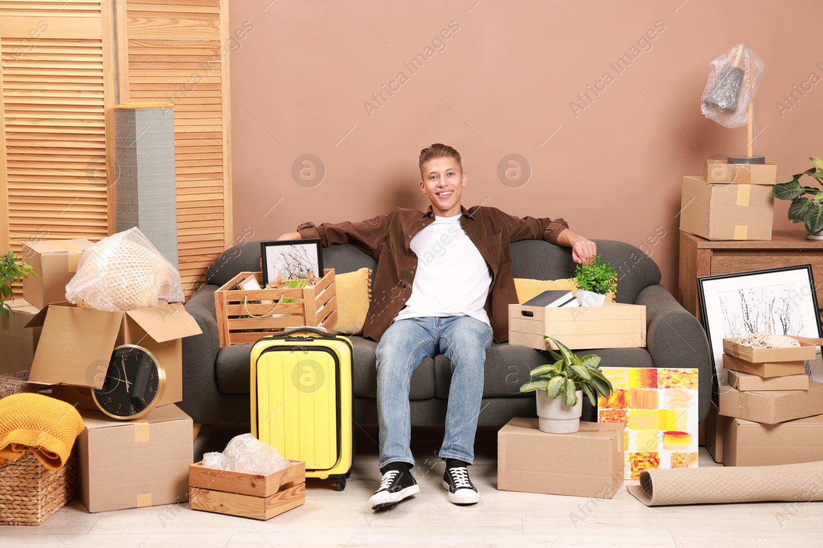 Photo of Happy man with different stuff in new apartment. Housewarming party