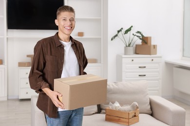 Photo of Happy man with moving box in new apartment. Housewarming party