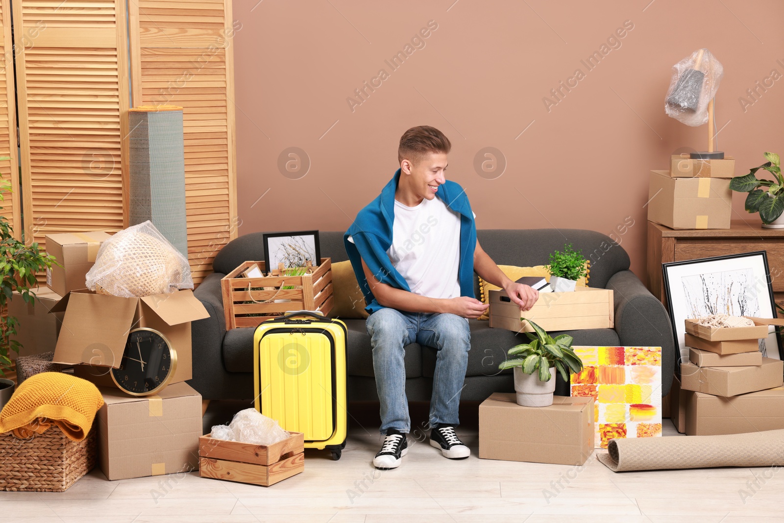 Photo of Happy man with different stuff in new apartment. Housewarming party