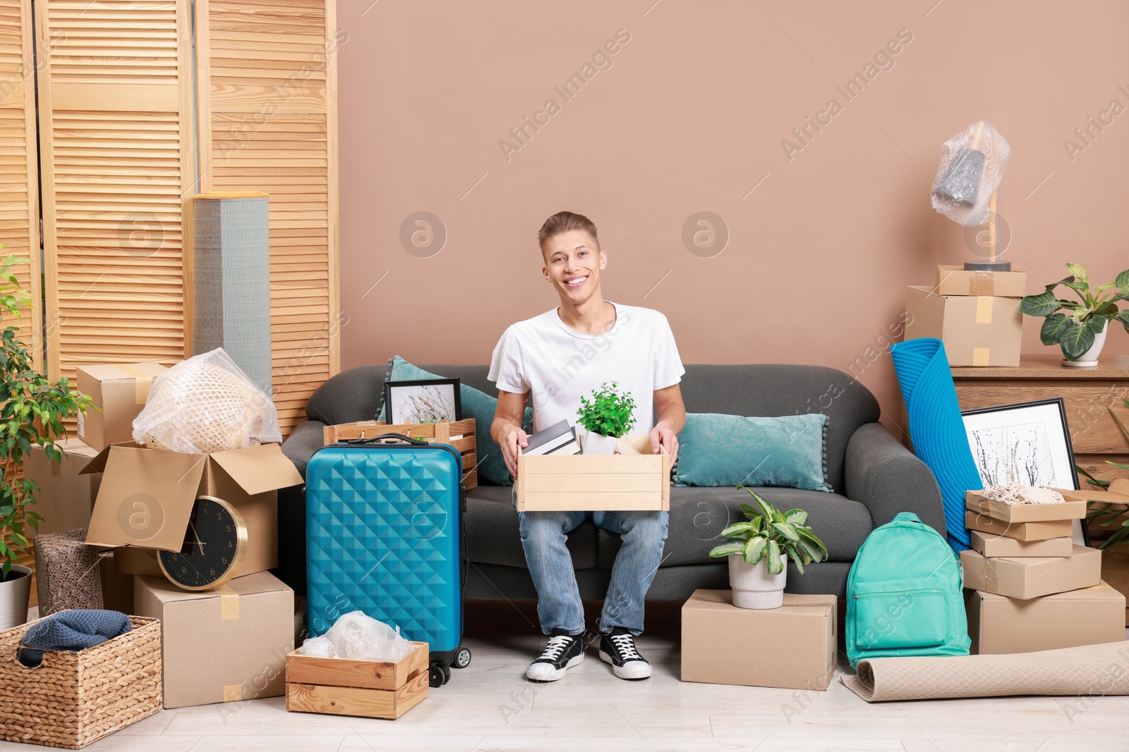 Photo of Happy man with different stuff in new apartment. Housewarming party