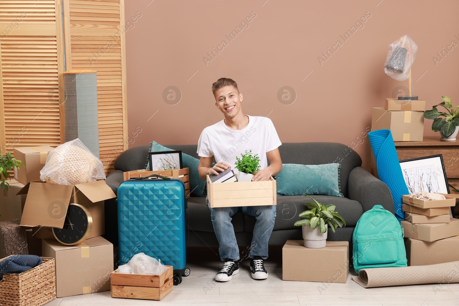 Photo of Happy man with different stuff in new apartment. Housewarming party