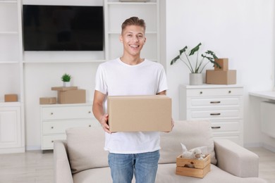 Photo of Happy man with moving box in new apartment. Housewarming party