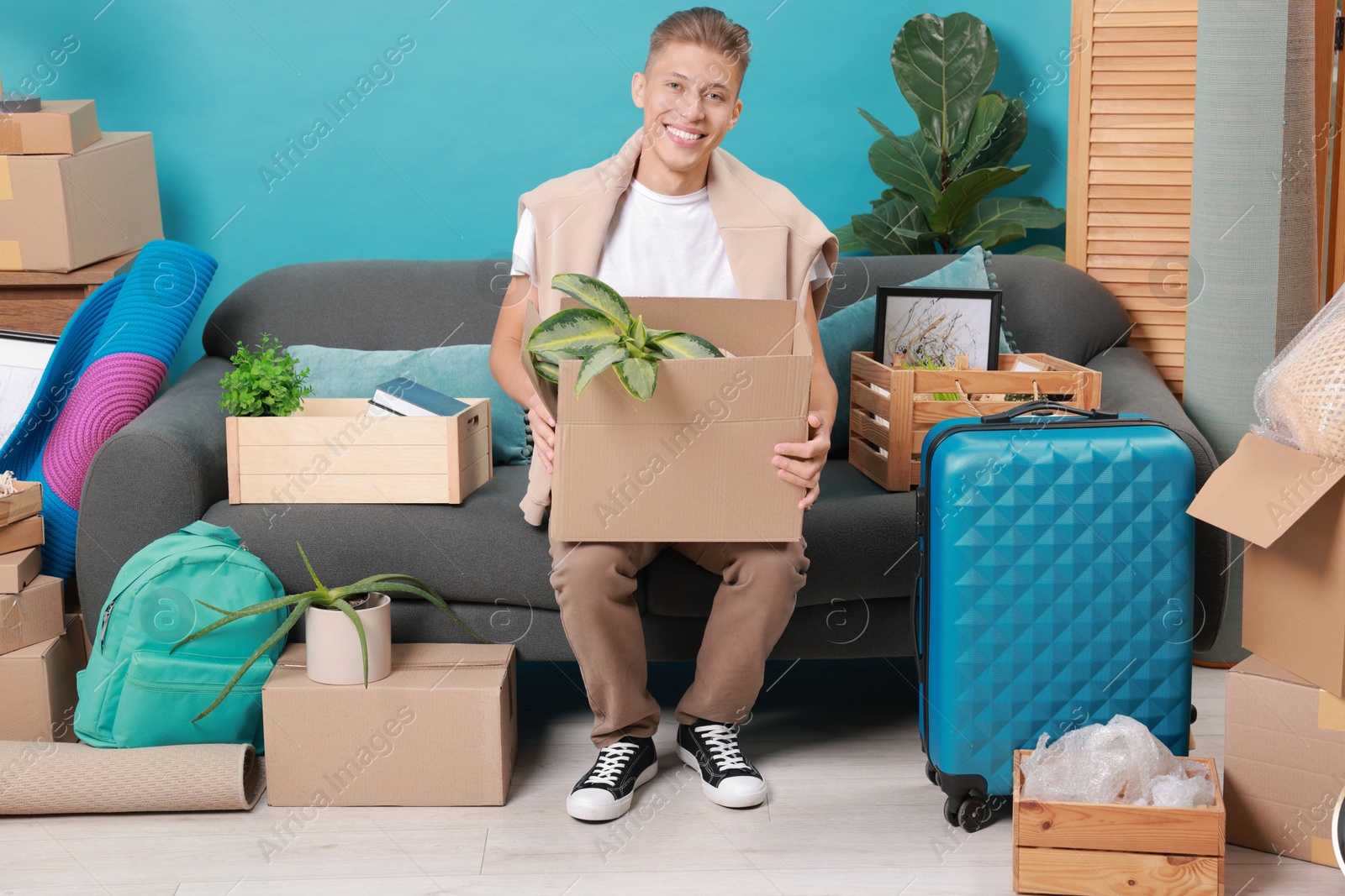 Photo of Happy man with different stuff in new apartment. Housewarming party