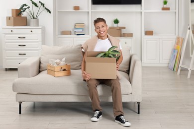 Photo of Happy man holding moving box with houseplant in new apartment. Housewarming party