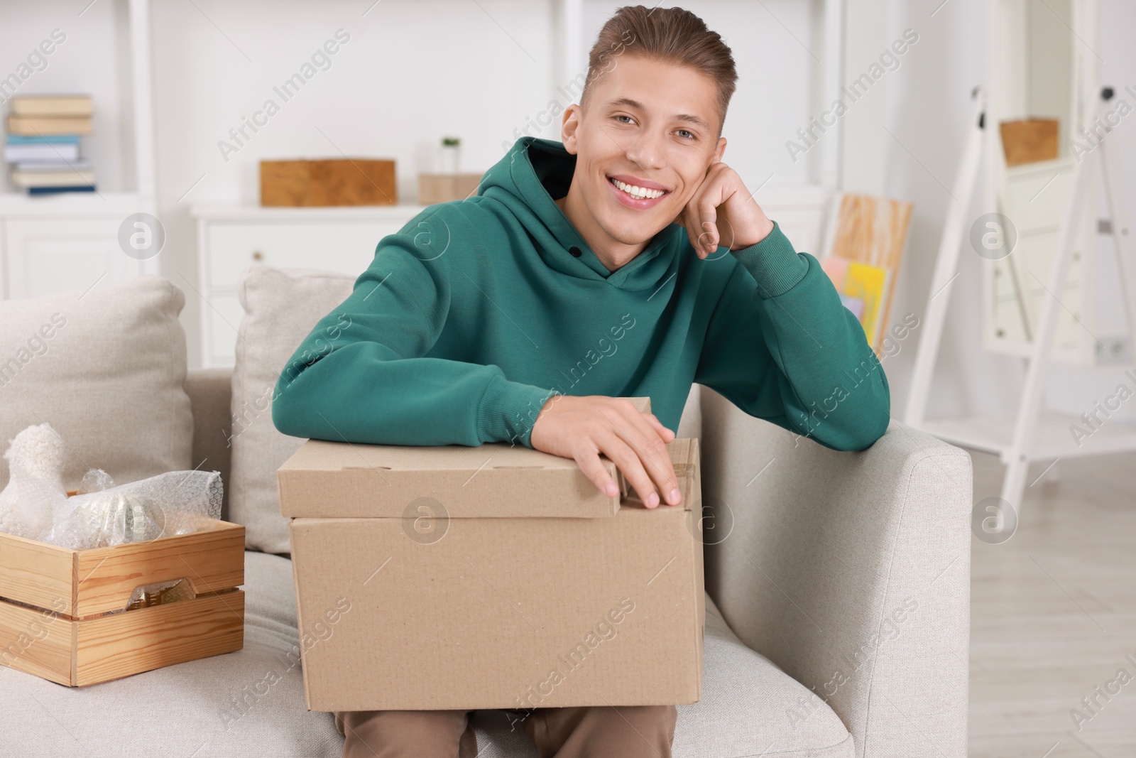 Photo of Happy man with moving boxes in new apartment. Housewarming party