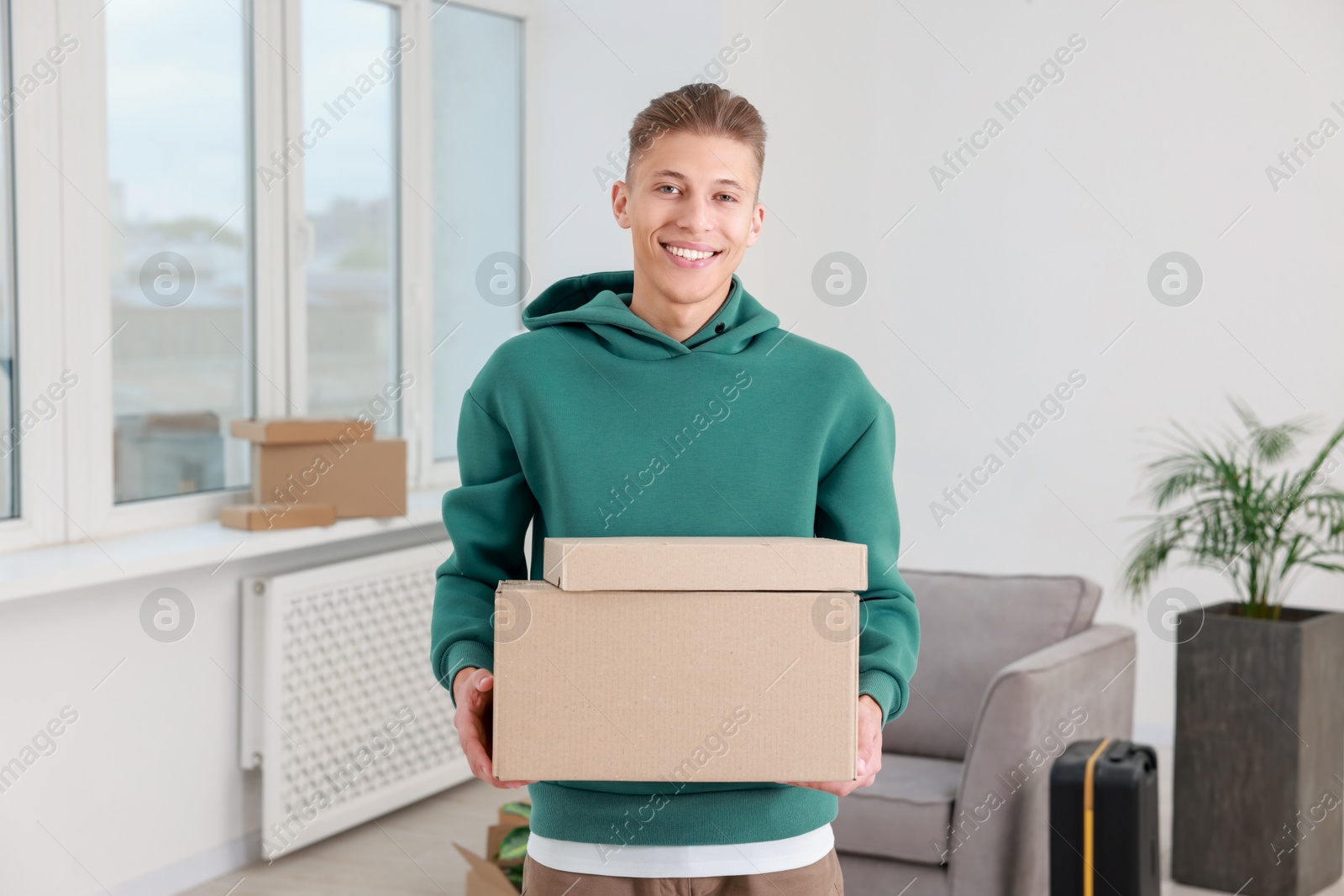 Photo of Happy man with moving boxes in new apartment. Housewarming party