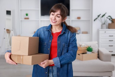 Photo of Happy woman with moving boxes in new apartment. Housewarming party