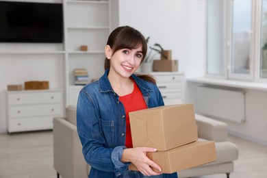 Happy woman with moving boxes in new apartment. Housewarming party