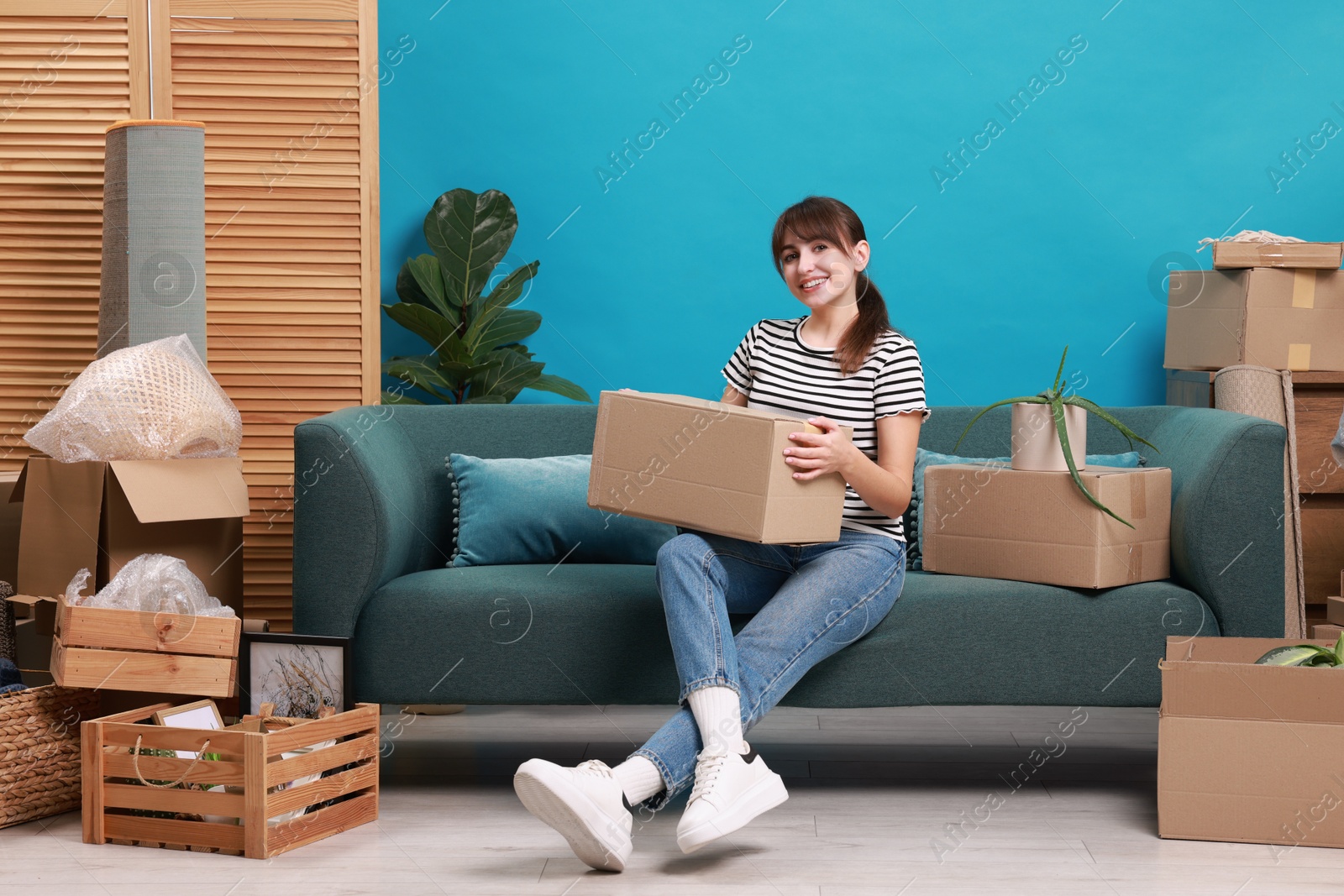 Photo of Happy woman with moving boxes in new apartment. Housewarming party