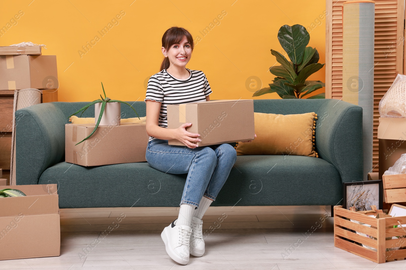 Photo of Happy woman with moving boxes in new apartment. Housewarming party