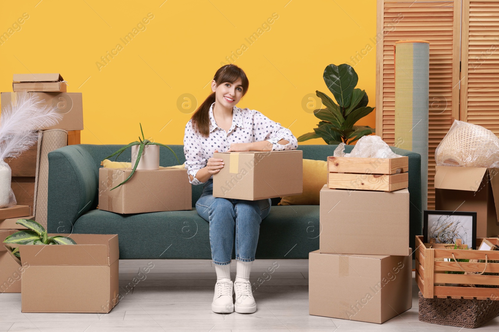 Photo of Happy woman with moving boxes in new apartment. Housewarming party