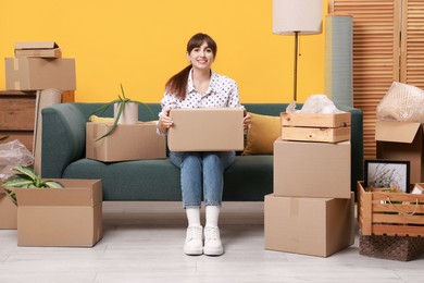 Photo of Happy woman with moving boxes in new apartment. Housewarming party