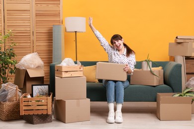 Photo of Happy woman with moving boxes in new apartment. Housewarming party