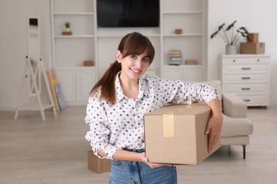 Photo of Happy woman with moving box in new apartment. Housewarming party