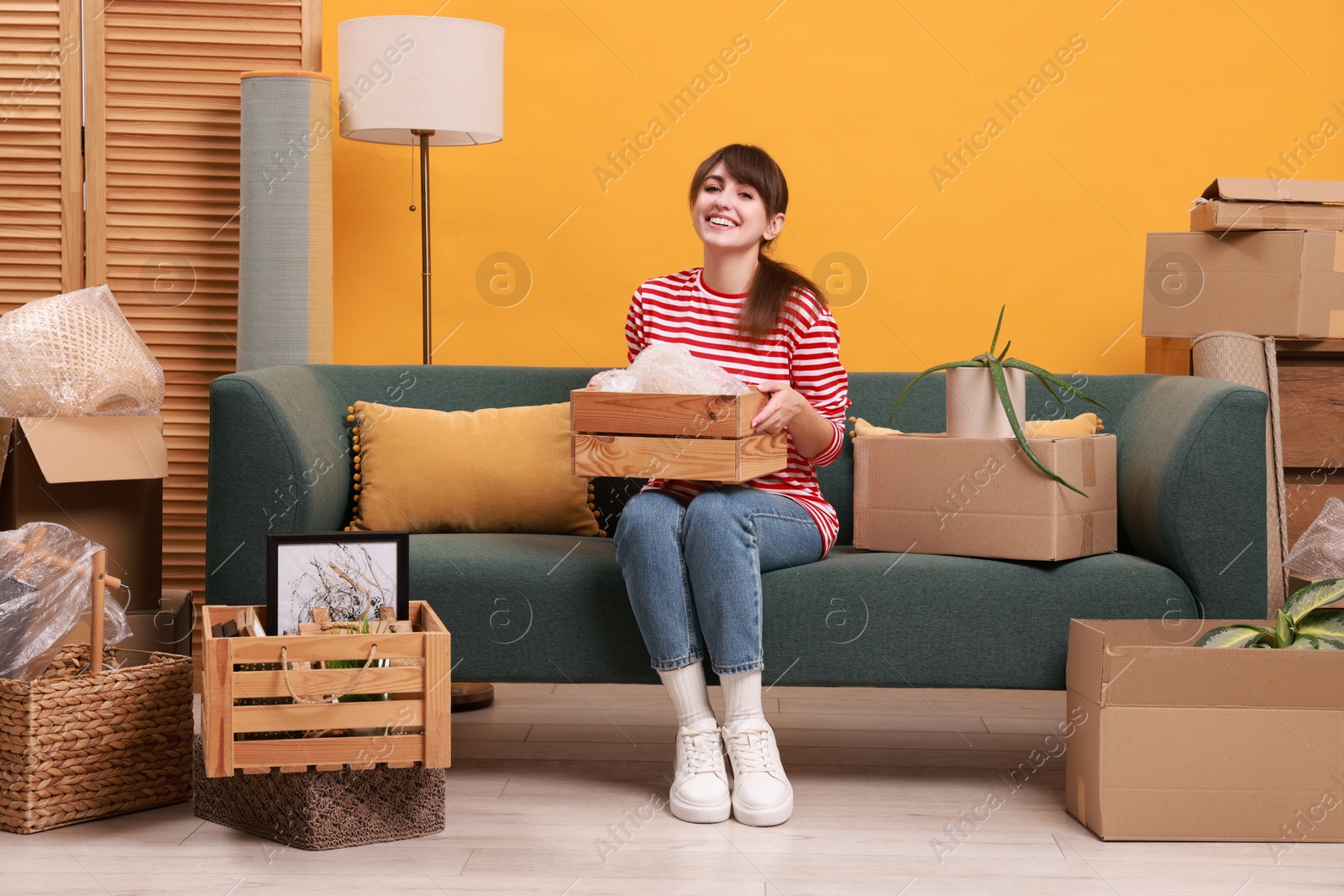 Photo of Happy woman with moving boxes in new apartment. Housewarming party