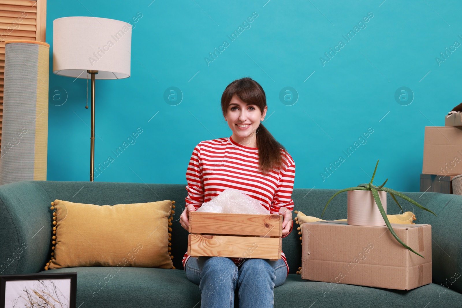 Photo of Happy woman with moving boxes in new apartment. Housewarming party