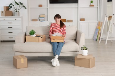 Photo of Happy woman with moving boxes in new apartment. Housewarming party