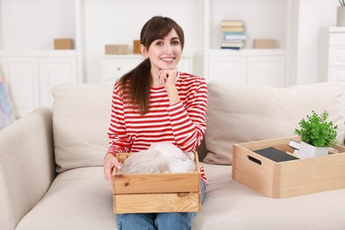 Photo of Happy woman holding wooden crate with stuff in new apartment. Housewarming party