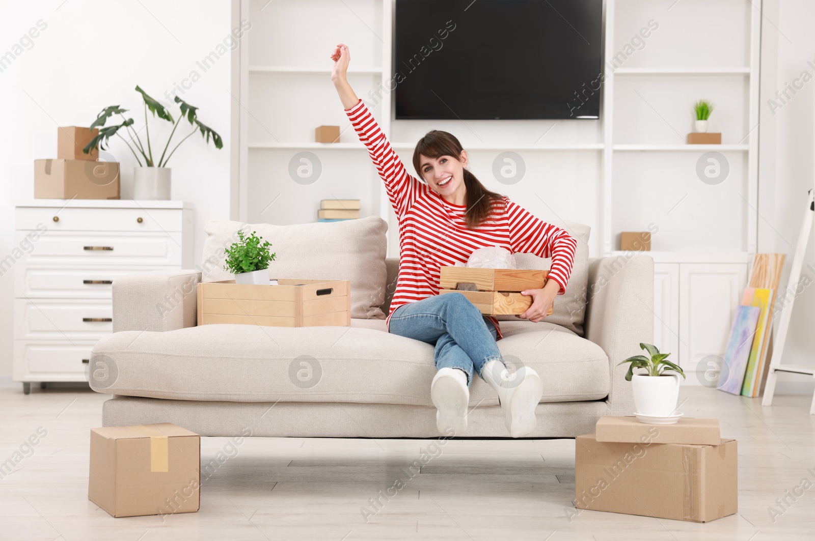 Photo of Happy woman with moving boxes in new apartment. Housewarming party