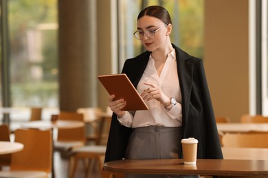 Photo of Woman in stylish formal suit with tablet indoors