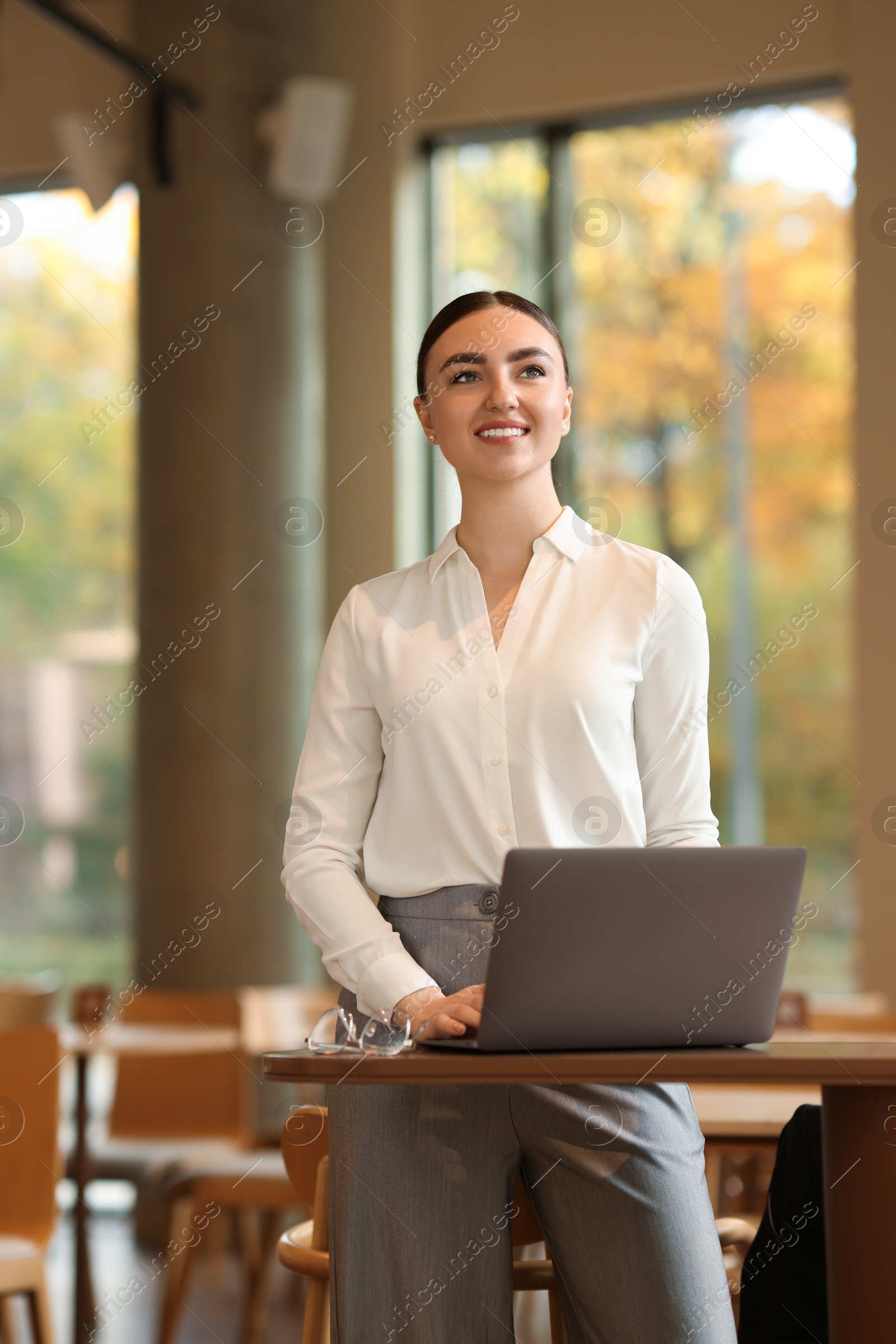 Photo of Beautiful woman in stylish outfit working on laptop indoors