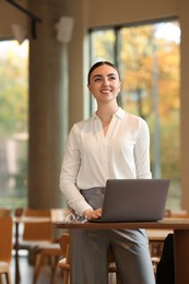 Photo of Beautiful woman in stylish outfit working on laptop indoors