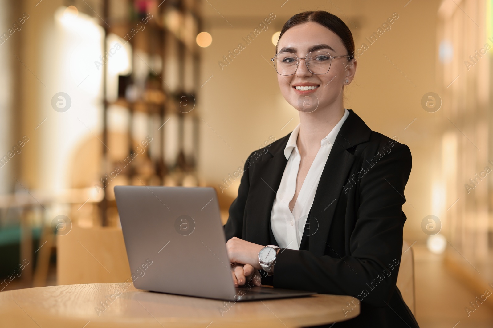 Photo of Woman in stylish formal suit working on laptop at table indoors