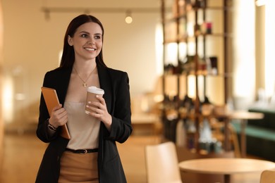 Woman in stylish formal suit with tablet and coffee indoors. Space for text