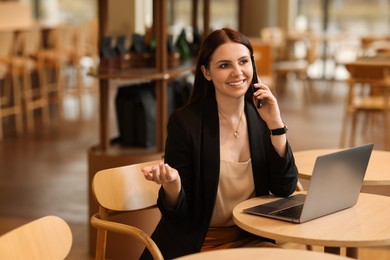 Photo of Woman in stylish formal suit working at table indoors