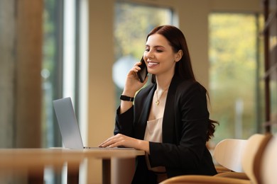 Woman in stylish formal suit working at table indoors