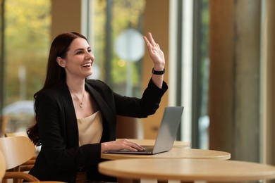 Photo of Woman in stylish formal suit greeting someone indoors